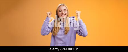 Trionfando festeggiando positivo capelli leale giovane vincitrice sollevare mani clench fists up vittoria risultato gesto vicino occhi sorridenti ampiamente Foto Stock