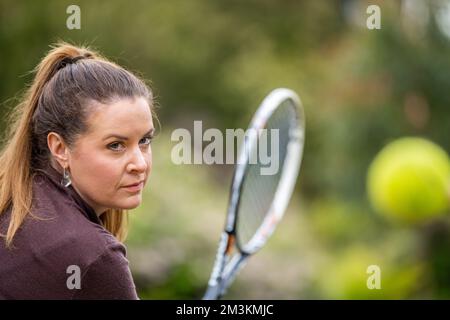 tennista femminile che pratica le mani in avanti e che colpisce le palle da tennis su un campo d'erba in inghilterra Foto Stock