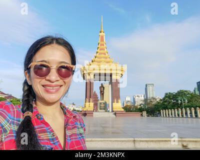 Una giovane donna turistica asiatica che prende un selfie alla Statua del Re Padre Norodom Sihanouk Memorial a Phnom Penh città, Cambogia. Foto Stock