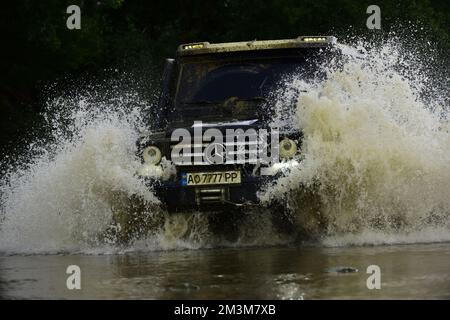 Fuoristrada camion sportivo tra le montagne paesaggio. Auto fuoristrada. Si schiantò in una pozza e raccolse uno spruzzo di sporcizia. Avventure all'aperto. Ruota chiusa Foto Stock