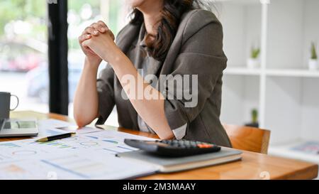 Stressato e professionale asiatico businesswoman o capo femmina siede al tavolo, pugni clenched, avendo una conversazione seria nella riunione con lei Foto Stock