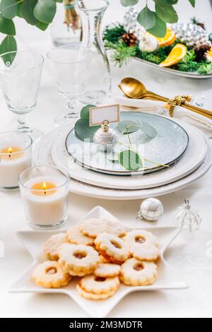 Tavolo di Natale con eucalipto, posate e candele in tonalità bianco e verde Foto Stock