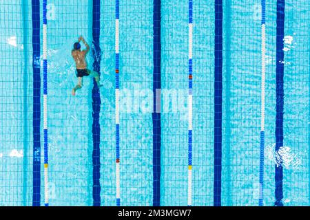 Concetto attivo di tempo libero. Uomo irriconoscibile nel nuotare da solo in una piscina. Scatto ad angolo alto. Foto di alta qualità Foto Stock