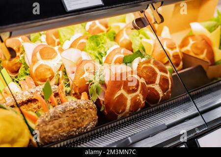 Varietà di gustosi panini con vari ripieni nella finestra di un negozio o supermercato. Spuntini e fast food Foto Stock