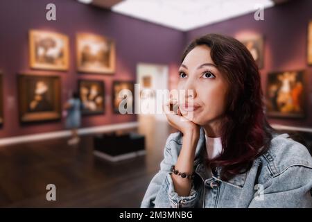 una bambina annoiata o studente in una galleria d'arte o in un museo guarda i capolavori degli artisti classici Foto Stock