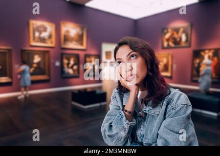 una bambina annoiata o studente in una galleria d'arte o in un museo guarda i capolavori degli artisti classici Foto Stock