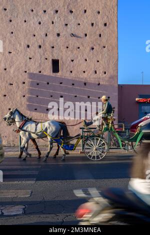 Cavallo e carrozza passando attraverso le mura della città alla porta Nuova a Marrakech, Marocco. Popolare tra i turisti lasciati in pullman per i tour di Marrakech. Foto Stock