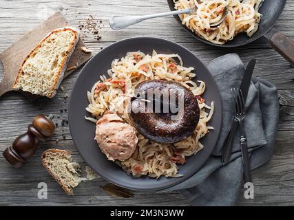 Morcilla di salsiccia sanguinata, rapa di sauer stufata e purè di patate con fagioli bruni primo piano. Piatto tradizionale sloveno con salsiccia di sangue arrosto Foto Stock