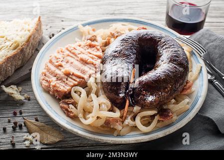 Morcilla di salsiccia sanguinata, rapa di sauer stufata e purè di patate con fagioli bruni primo piano. Piatto tradizionale sloveno con salsiccia di sangue arrosto Foto Stock