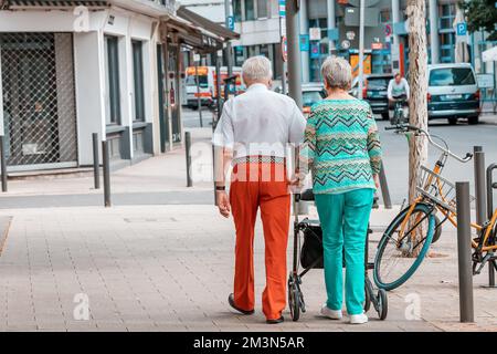 31 luglio 2022, Colonia, Germania: Una coppia anziana di amanti della moda cammina lungo una strada cittadina o va a fare shopping per i vestiti Foto Stock