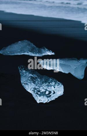 Primo piano pezzi di ghiaccio trasparenti su sabbia scura concept foto Foto Stock
