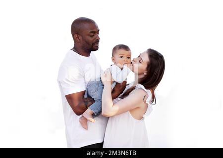 Famiglia multirazziale felice. Mamma caucasica e papà afro-americano baciano il bambino piccolo. Genitori, Ritratto di madre, padre e bambino sulle mani isolato su w Foto Stock