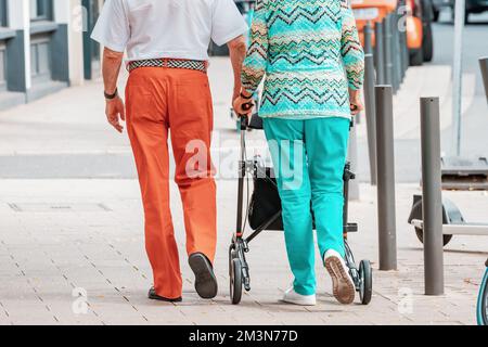 31 luglio 2022, Colonia, Germania: Una coppia anziana di amanti della moda cammina lungo una strada cittadina o va a fare shopping per i vestiti Foto Stock