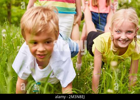 Gruppo di bambini che giocano alla gara di carriola in estate in natura Foto Stock