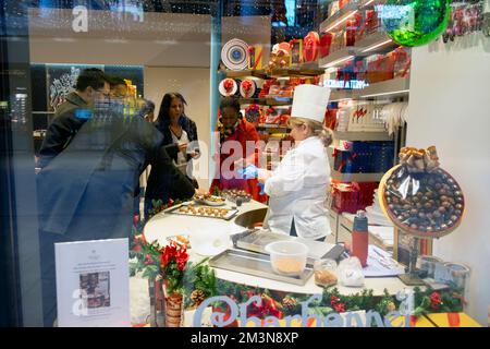 Vista dalla finestra di Charbonnel et Walker, dipendente del negozio di cioccolato e clienti a Natale, degustazione di cioccolatini nel negozio Broadgate London UK 2022 Foto Stock