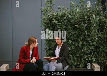 Primo piano di due fantastiche donne in affari che parlano mentre si siedono sulla panchina Foto Stock