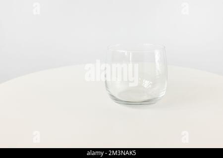 Svuotare il piccolo succo, l'acqua o il bicchiere da dessert su sfondo bianco del tavolo, spazio per la copia Foto Stock