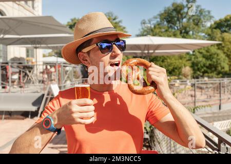 Ragazza con un bicchiere di birra e un tradizionale pretzel tedesco snack in biergarten o bar all'aperto Foto Stock