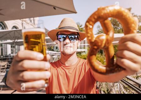 Ragazza con un bicchiere di birra e un tradizionale pretzel tedesco snack in biergarten o bar all'aperto Foto Stock