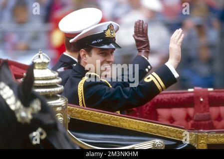 Il principe Andrew, Duca di York, ondeggia alla folla lungo il percorso per Westminster Abbey, mentre viaggia con suo fratello e sostenitore, il principe Edward (Conte di Wessex) il giorno del suo matrimonio. Sposò Sarah Ferguson all'Abbazia il 23 luglio 1986. 1986 Foto Stock
