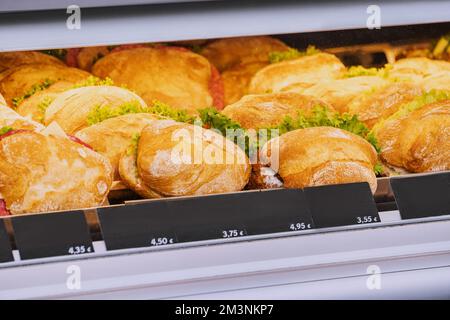 Varietà di gustosi panini con vari ripieni nella finestra di un negozio o supermercato. Spuntini e fast food Foto Stock
