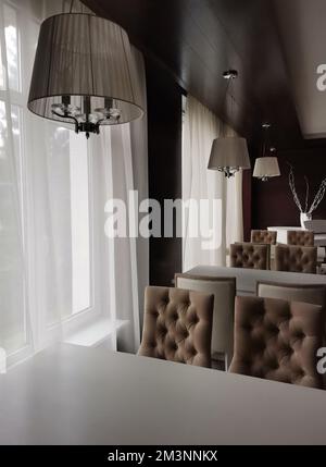 Dettagli interni del ristorante dell'hotel con lampadari in tessuto appesi sopra i tavoli con sedie lungo le finestre Foto Stock