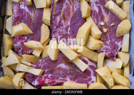 cibo fatto in casa, bistecche con patatine fritte pronte al forno. Ingredienti bistecca di maiale, patate, sale, olio, burro, origano e pepe Foto Stock