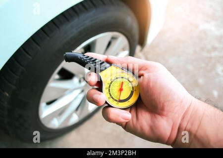 Il conducente tiene in mano un manometro standard per la manutenzione automatica Foto Stock