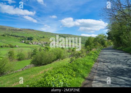 Guardando verso sud su Swaledale, a Gunnerside. Strada stretta. Fienili e pareti di pietra a secco modelli famosi. Accanto al fiume Swale, dal B6270; Yorkshire Dales Foto Stock