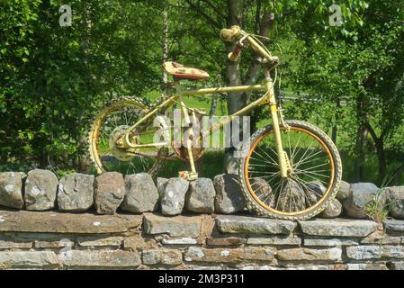 Bicicletta gialla sulla parete a Swaledale, vicino al villaggio di Gunnerside, dal B6270; vicino a Richmond, Yorkshire Dales National Park, North Yorkshire, England, U. Foto Stock