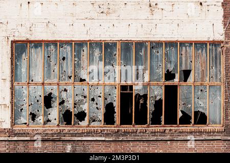 Costruzione in zona industriale con finestre rotte da pietre, proiettili e cesarei. Il concetto di conflitto militare, ghetti e teoria sociale di rotto Foto Stock