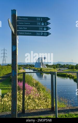 Guardando a nord verso il Kelpies con fiori selvatici luminosi e colorati sulla Forth e Clyde Canal Bank. Segnalatore e rilevatore di direzione. Parco pubblico Helix, Foto Stock