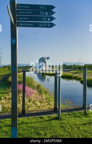 Guardando a nord verso il Kelpies con fiori selvatici luminosi e colorati sulla Forth e Clyde Canal Bank. Segnalatore e rilevatore di direzione. Parco pubblico Helix, Foto Stock