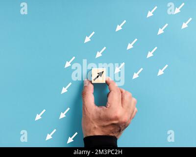 Unico, diverso, individualità. Nuota contro il ruscello e si alza fuori dalla folla. Mano maschile che posiziona un blocco di legno con un poi opposto Foto Stock