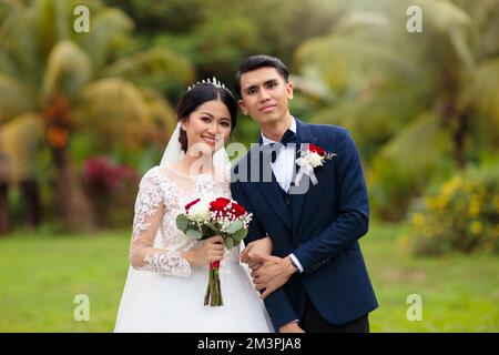 Sposa e sposo il giorno del matrimonio. Bella giovane coppia asiatica. Uomo e donna appena sposati. Sposato appena marito e moglie in abito da sposa. Foto Stock