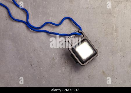 una mini luce portachiavi con una stringa blu che funziona per l'illuminazione di emergenza Foto Stock