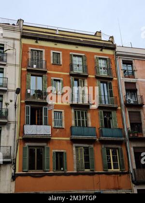 Vecchio edificio di appartamenti con un'interessante facciata arancione e cornici verdi delle finestre e balconi. Distretto di Born. Barcellona, Catalogna, Spagna. Foto Stock