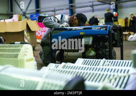 Un volontario pulisce un generatore elettrico, con radiatori elettrici davanti. Preparativi in corso e materiale pronto a partire per l'Ucraina attraverso l'associazione Ucraina Libre Tolosa. Sala 9 del Parc des Expositions sull'Ile du Ramier. Francia Tolosa il 15 dicembre 2022. Foto di Patricia Huchot-Boissier/ABACAPRESS.COM Credit: Abaca Press/Alamy Live News Foto Stock