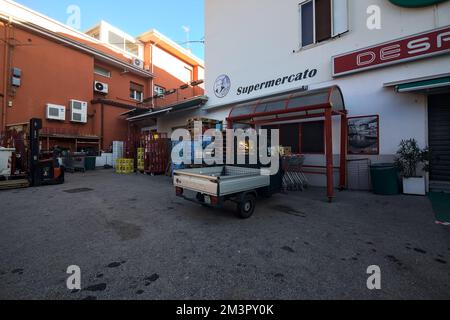 Piazza di fronte ad un negozio con un Ape Piaggio parcheggiato Foto Stock