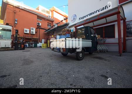 Piazza di fronte ad un negozio con un Ape Piaggio parcheggiato Foto Stock