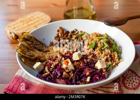 vista sul piatto di legno della ciotola vegetariana invernale con cavolo rosso, funghi, tofu, cereali farro, indivia e radicchio. Esempio di mare d'inverno o d'autunno Foto Stock