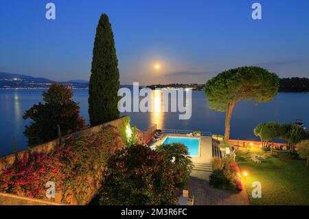 Un bellissimo giardino e piscina sul Lago di Garda. Scatto notturno dall'atmosfera suggestiva. Foto Stock