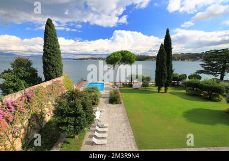 Un bellissimo giardino e piscina sul Lago di Garda. Scatto panoramico dall'atmosfera suggestiva. Foto Stock