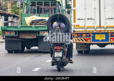 SAMUT PRAKAN, THAILANDIA, MAGGIO 21 2022, l'uomo porta grandi pneumatici su una moto, Foto Stock