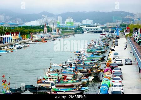 Un porto con colorate barche da pesca e auto nella città di Busan, Corea del Sud Foto Stock