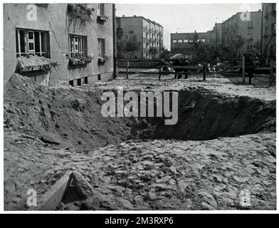Grande cratere di bomba in una strada di Varsavia accanto ad una casa che appare strutturalmente intatta, nonostante la perdita delle sue finestre in l'esplosione che è venuto come conseguenza dell'assedio tedesco e incursioni aeree sulla capitale nel settembre 1939. Settembre 1939 Foto Stock