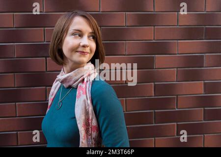 Primo piano giovane donna su sfondo muro di mattoni Foto Stock