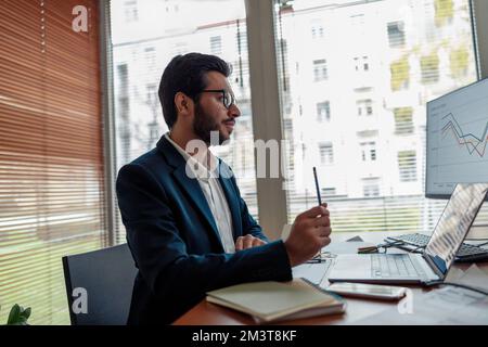 Occupato uomo d'affari indiano in tuta che lavora su progetto da casa ufficio Foto Stock