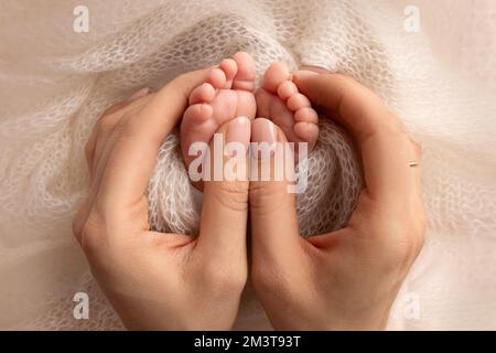 La madre sta facendo il massaggio sul suo piede del bambino. Piedi del bambino del primo piano nelle mani della madre. Foto Stock