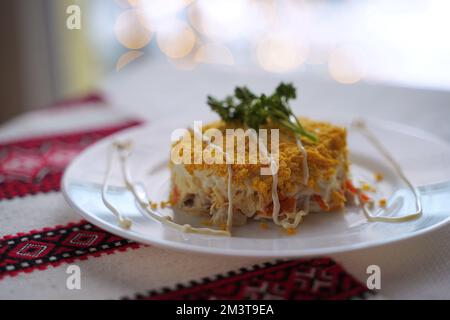 Insalata di mimosa fatta in casa. Cibo tradizionale ucraino sul tavolo con tovaglia ricamata. Foto Stock